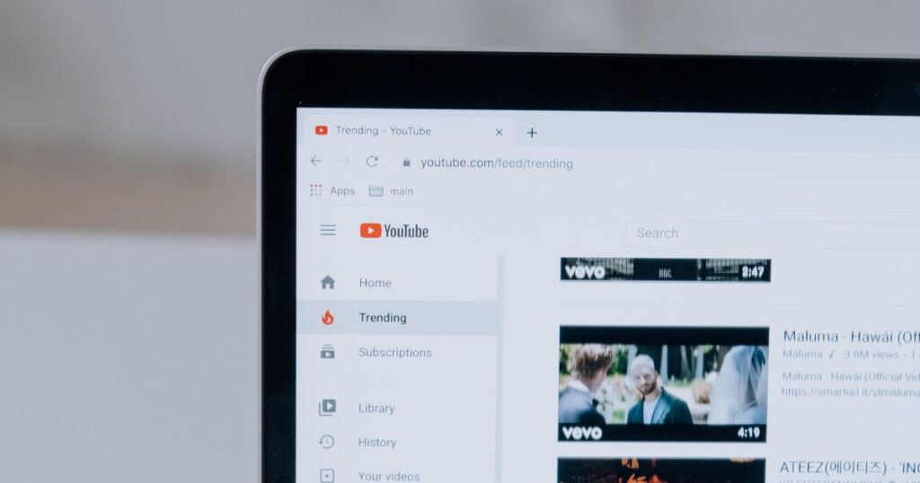 Closeup of a laptop, tablet, or iPad screen showing the left-hand menu for YouTube and the trending feed thumbnails.