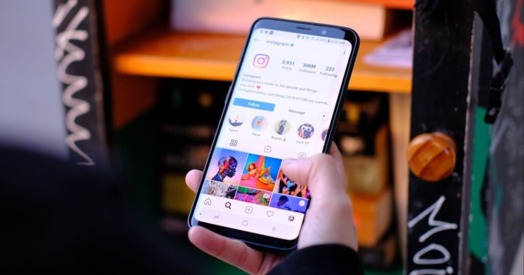 Closeup of a person's hand holding a smartphone and scrolling on the Instagram app.