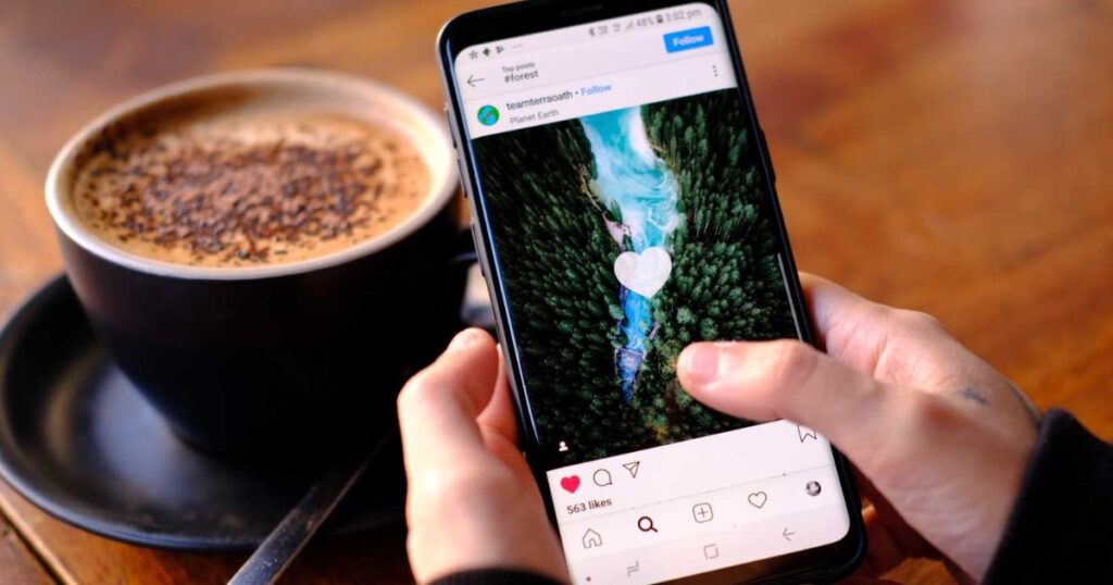 Closeup of person's hands holding a smartphone with a social media image post they are tapping Like on.