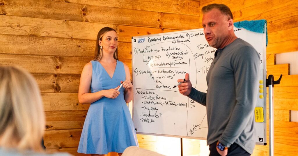 Matt standing in front of a whiteboard, having a discussion with two women.