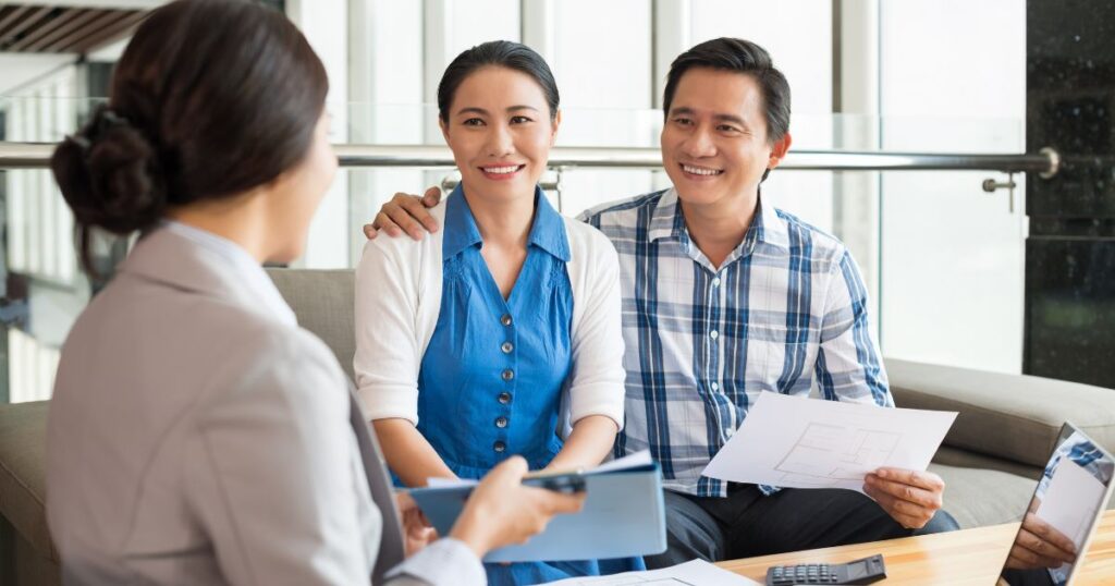 A smiling couple going over paperwork with their agent.