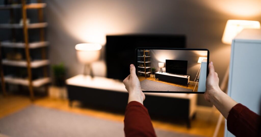 Unidentified woman using a tablet or iPad to photograph a living room or a family room setting.