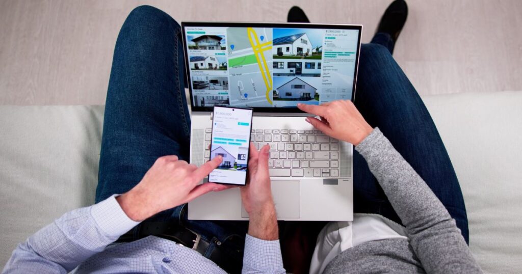 Unidentified couple viewing real estate listing on a laptop and smartphone.