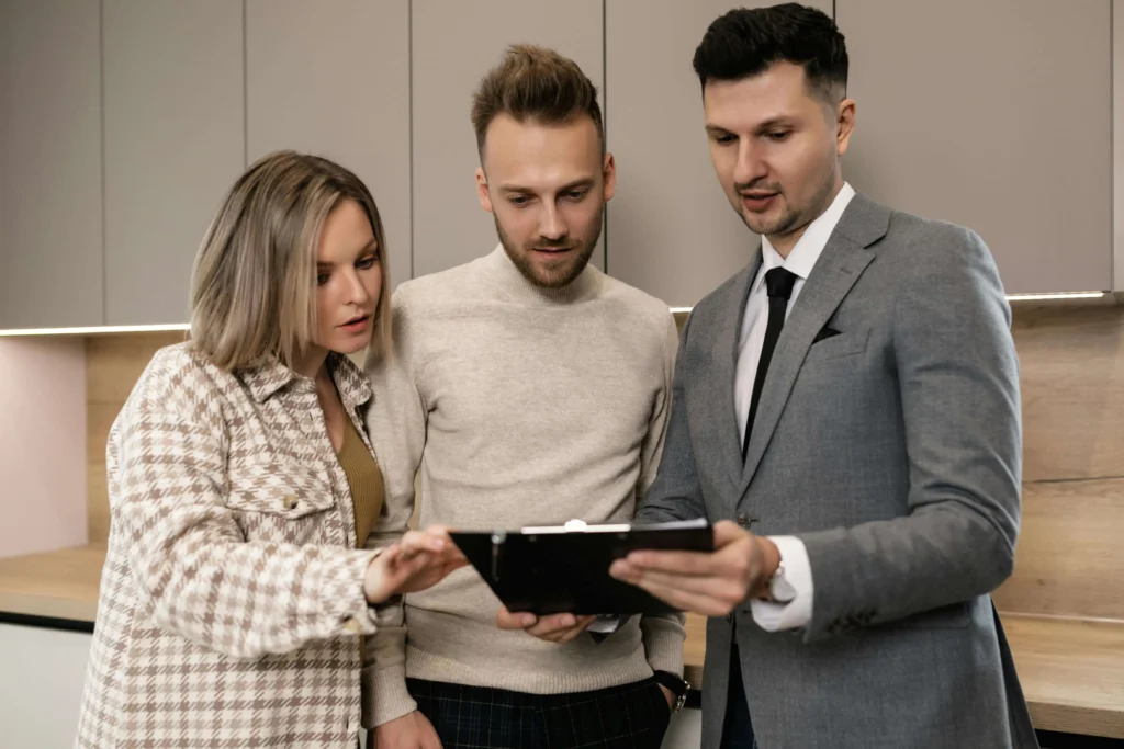 Two young men and young woman looking at paperwork on a clipboard one of the men is holding.