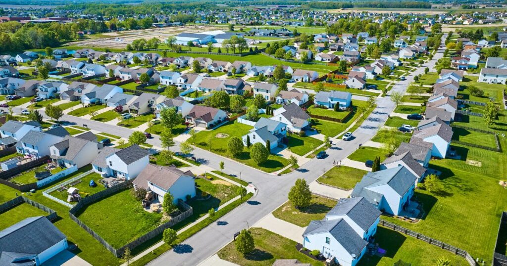 Aerial view of a residential neighborhood with large yards and forested area nearby.