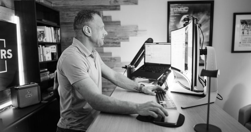 Matt standing at a counter-height desk typing on a keyboard while looking at a computer monitor.