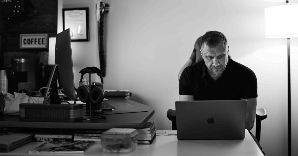 Matt Tompkins seated at his desk while working on an Apple laptop.