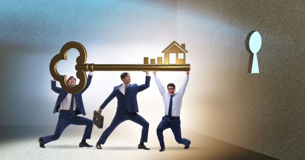 Three young men in business attire holding up a giant brass skeleton key with the shape of a house as part of the key's teeth.