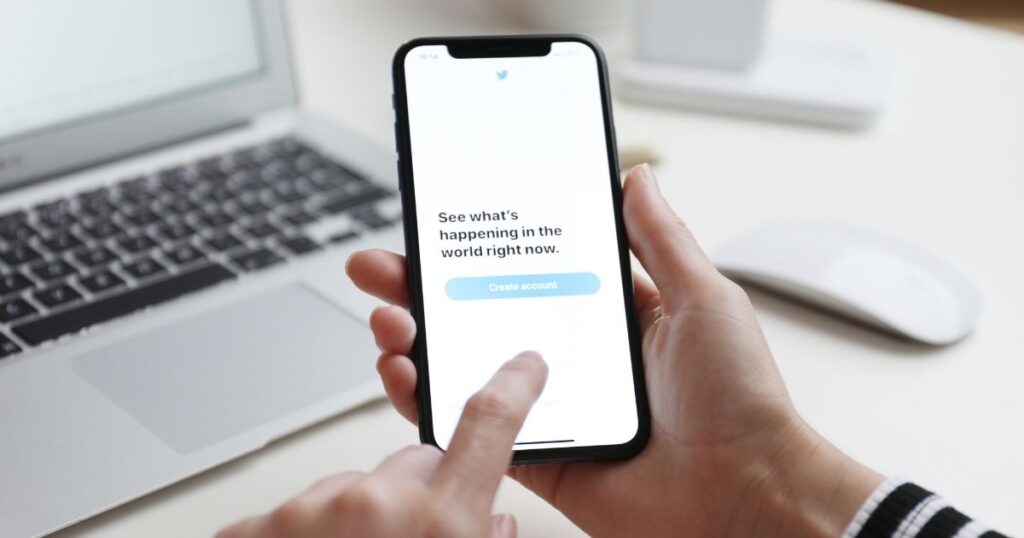 Closeup of person's hands holding a smartphone, ready to click on a "Create Account" button on the screen.