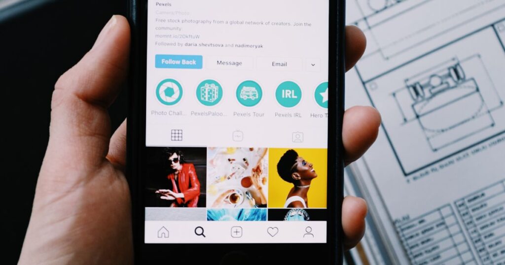 Closeup of a person's hand holding a smartphone with a social media account on the screen.
