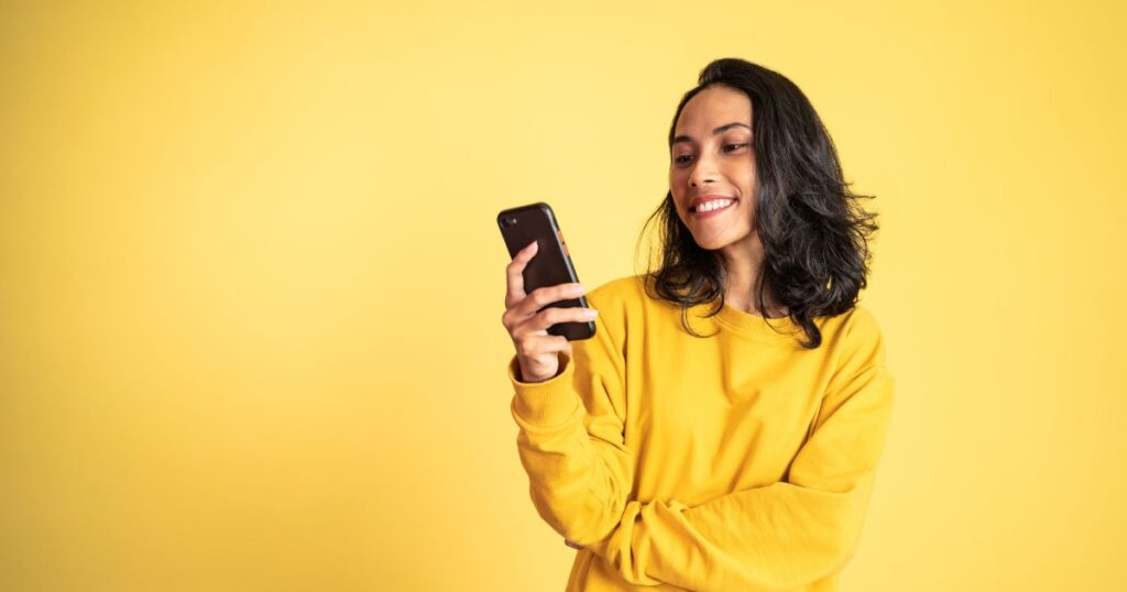 A smiling woman looking at her smartphone.