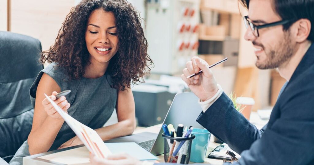 Woman and man at an office desk reviewing paperwork.