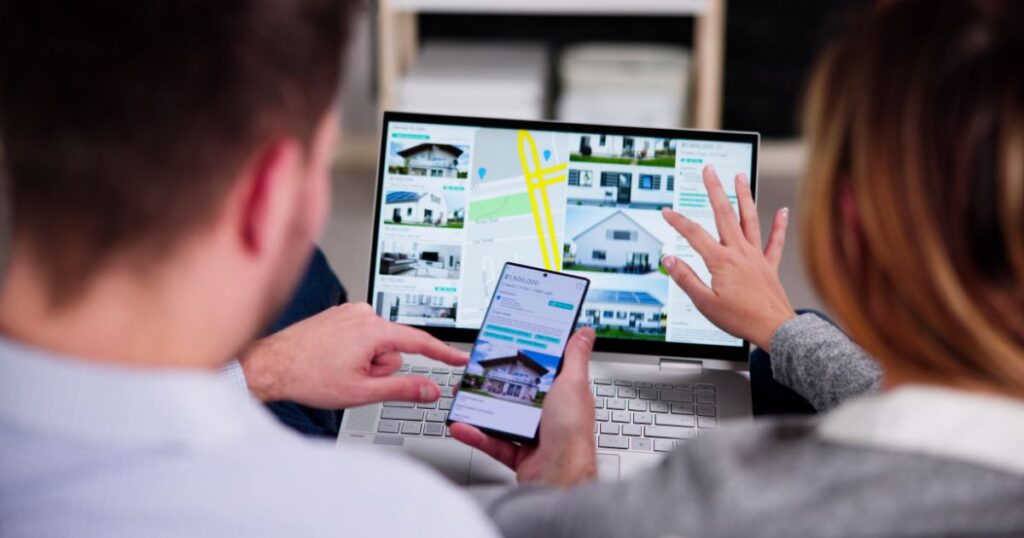 Unidentified couple comparing real estate listings on a laptop and a smartphone.