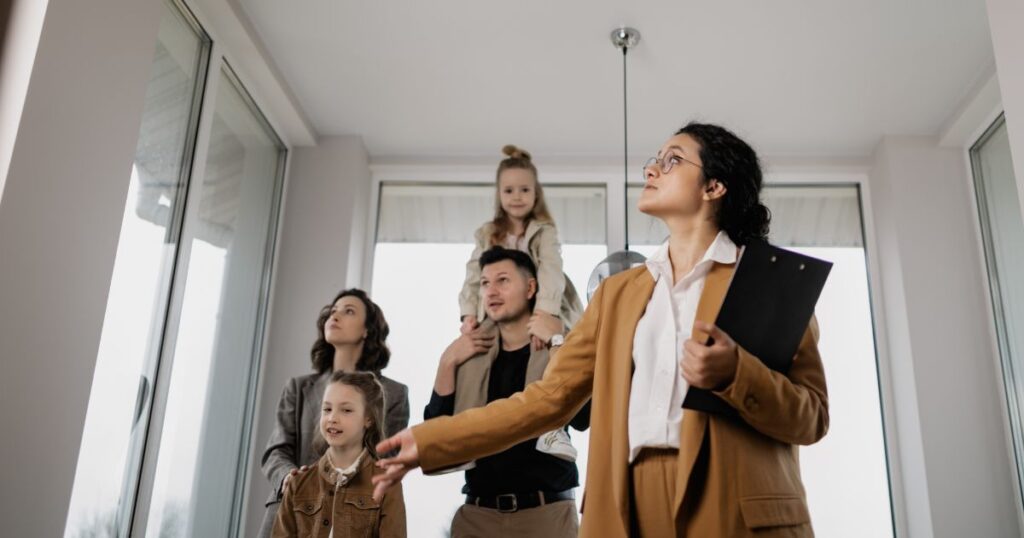 Female real estate agent showing a property to a couple with two children.