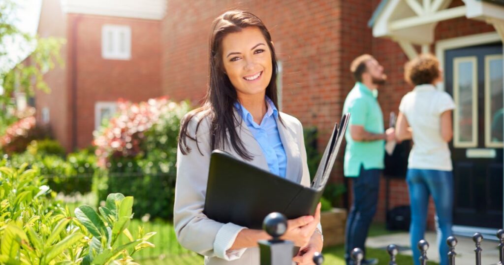 Smiling female realtor at a property tour with clients.