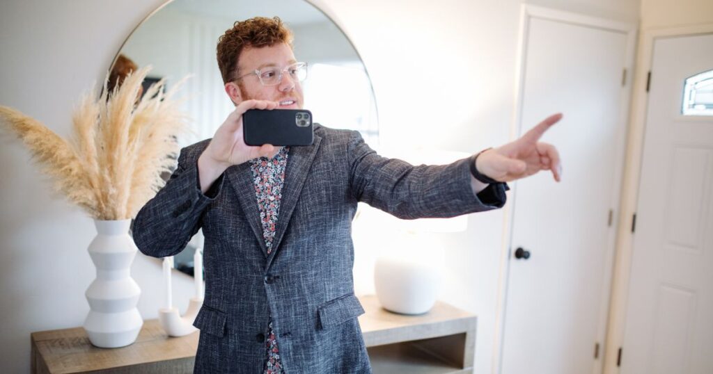 Male agent recording property listing media on his smartphone.