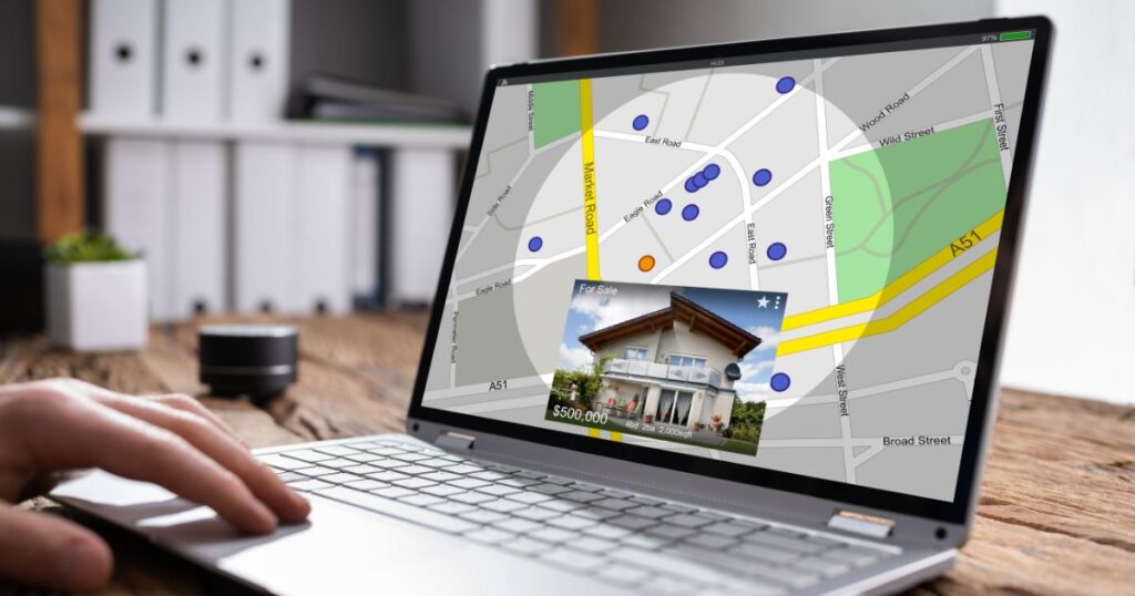 Person using a laptop with the screen showing a real estate listing and a mapping feature behind it.