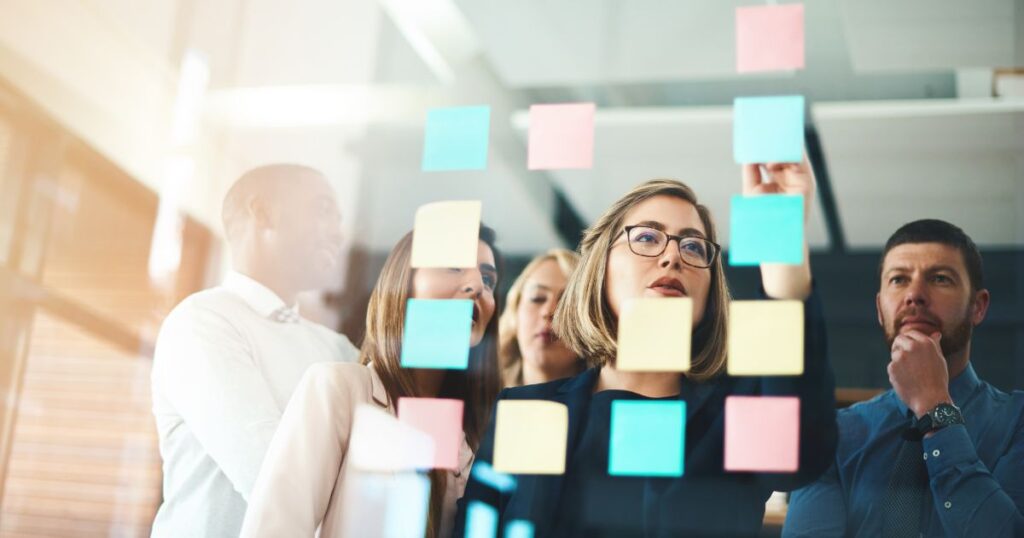 A small real estate team looking at Post-Its arranged on a window.
